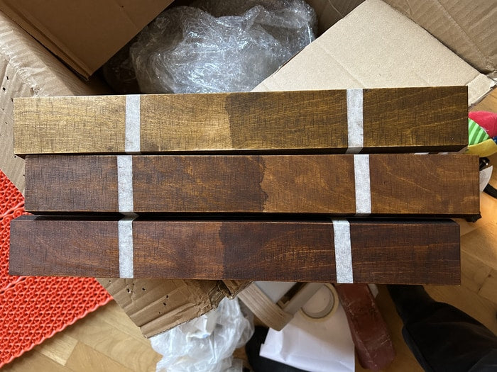 Three painted wood test pieces side by side, showing a light stain, a mid brown and a dark brown finish