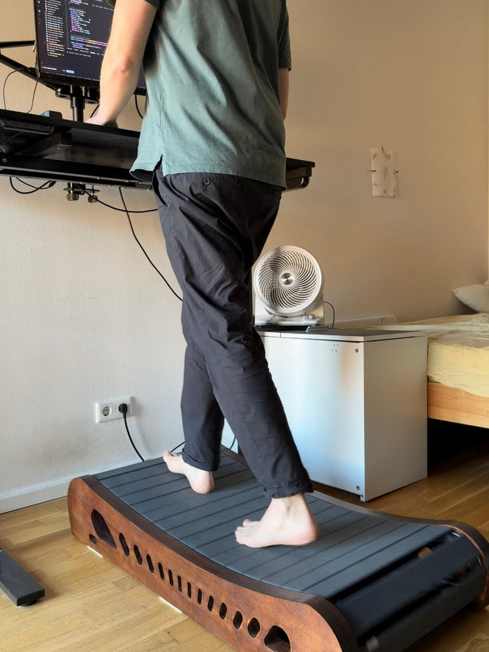 Barefoot walking on the dark brown Office Walker with dark gray slats at a standing desk
