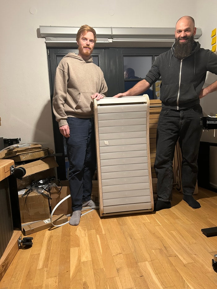 Marvin and Johannes with an Office Walker prototype stood on end in the workshop